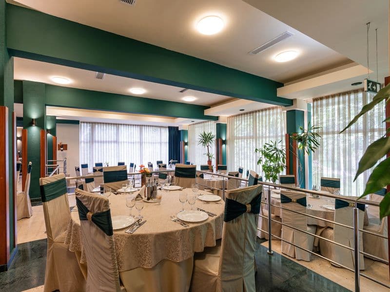 Masă rotundă servită în restaurantul Complexului Bradul-Călimani, văzută de lângă balustrada din sală