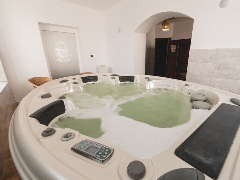 Jacuzzi-ul spa-ului Hotelului Carol văzut de aproape, cu tetiere negre și panoul de comandă