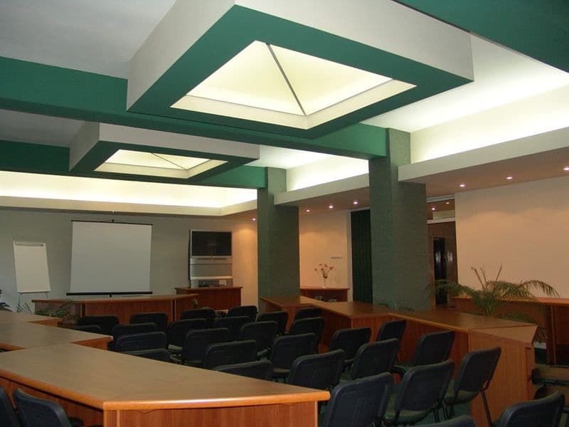 Sala de conferințe a Complexului Bradul-Călimani, cu mese în U, scaune negre, flipchart, ecran de proiecție și luminatoare în tavan